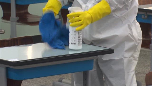 Person Sanitizing Chair in the Classrooms in Protective Suit