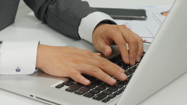 Hands typing on a laptop at an office desk