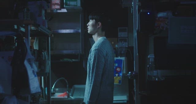Man in a dimly lit room surrounded by shelves and equipment