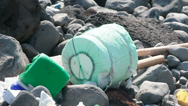 Rocky coastal area littered with various types of waste