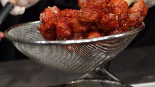 Fried meatballs being drained in a strainer