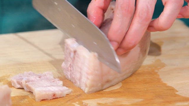 Slicing boiled pork on a cutting board