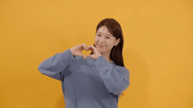 Long haired woman making heart with hands with happy expression