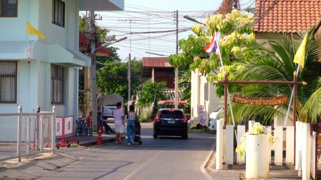People walking through a peaceful Thai village on a sunny afternoon