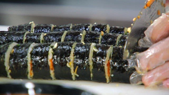 Slicing freshly made kimbap rolls