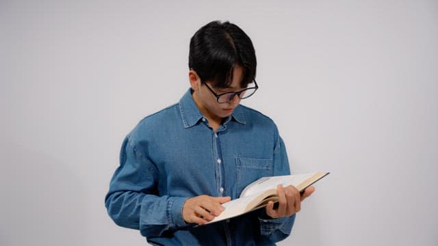 Man wearing glasses reading a book in a quiet room
