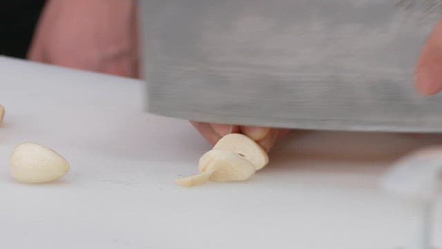 Cutting Garlic with a Knife on a Cutting Board