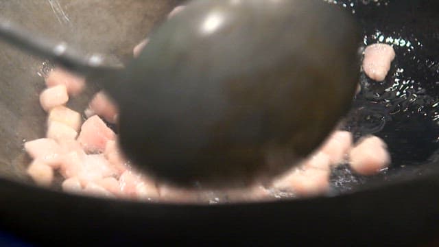 Diced lard being stir-fried in a pan