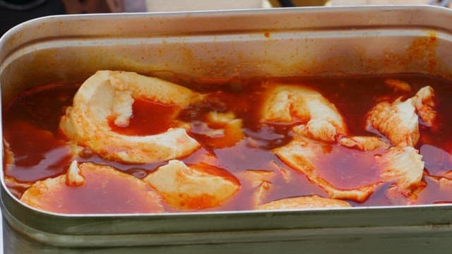Adding ramen noodles to soft tofu stew cooked in a portable metal pot