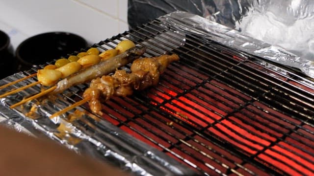 Skewered meat grilling over hot coals