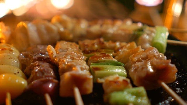 Sprinkling pepper on skewers cooked on hot pan