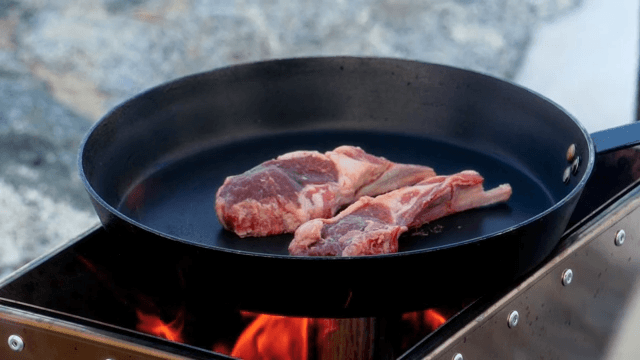 Fresh lamb being cooked in a frying pan on the portable stove