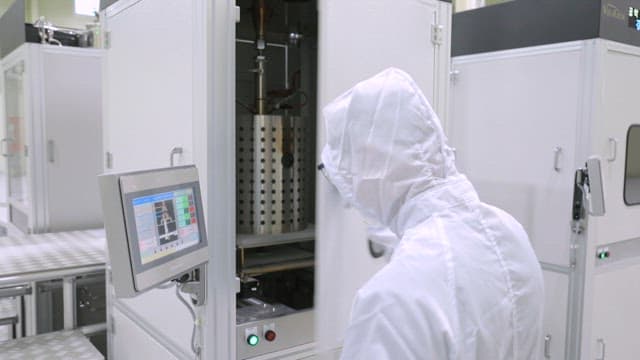 Lab technician operating industrial machine in a cleanroom environment
