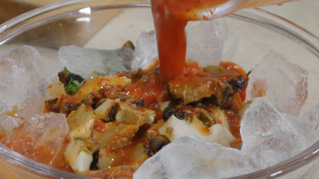 Pouring Spicy Sauce into a Glass Bowl with Ice and Conches