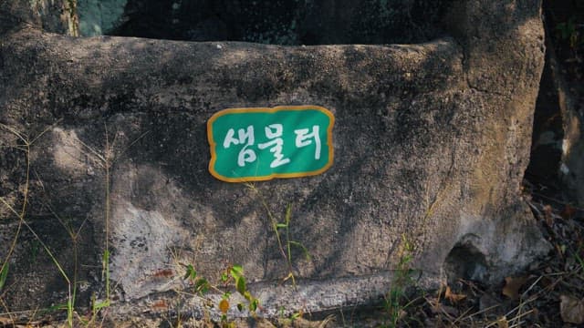 Green name tag for an old spring water site made of rock