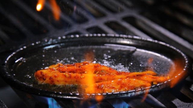 Spicy seasoned grilled deodeok cooked on a hot iron plate