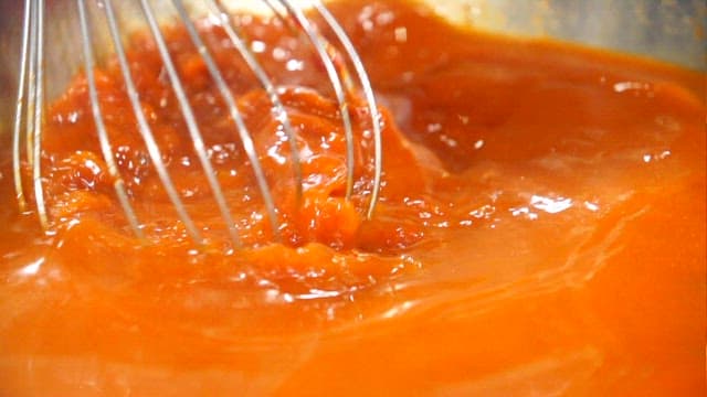 Mixing gochujang and water in a bowl with a whisk
