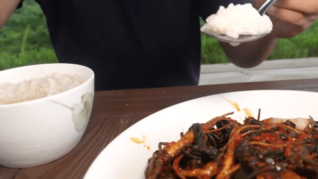 Person enjoying a meal with kimchi and riceoutdoors with a serene background
