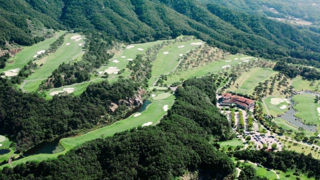 Green Golf Course Located at the Foot of a Lush Mountain