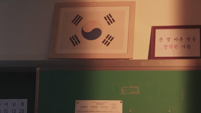 Classroom wall with a framed Korean flag in warm sunlight.