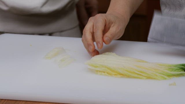 Preparing cabbage on a white cutting board in the kitchen
