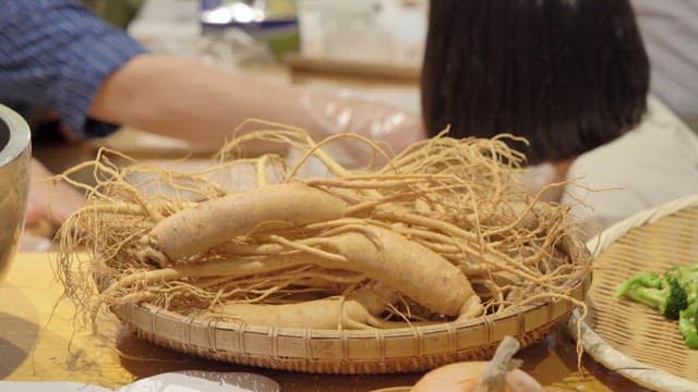 Ginseng on a basket with people preparing food