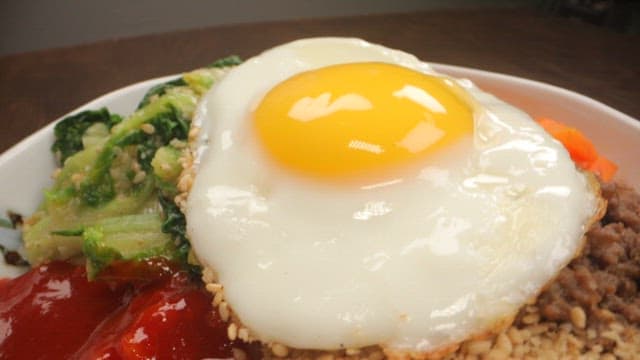 Bowl of fresh bibimbap with fresh vegetables and fried egg