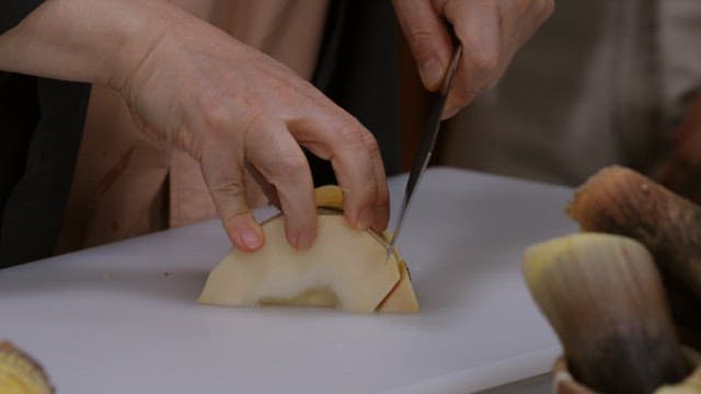 Cutting boiled bamboo shoots with a knife on a cutting board