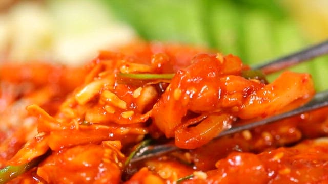 Chopstickful of spicy and sour swordtip squid salad with sesame seeds