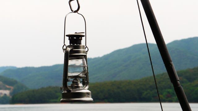 Lighting an camping oil lantern by the lake in the afternoon with a mountain view