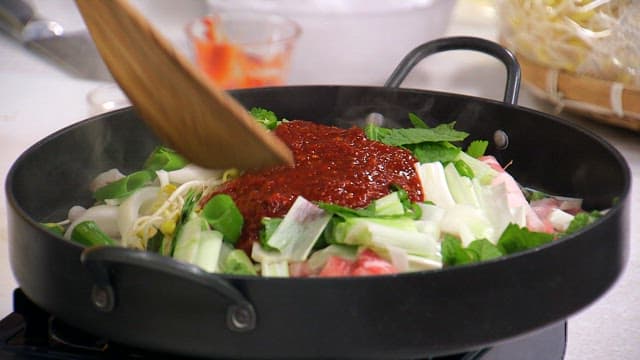 Bean sprout bulgogi cooked on a hot plate with a wooden spatula