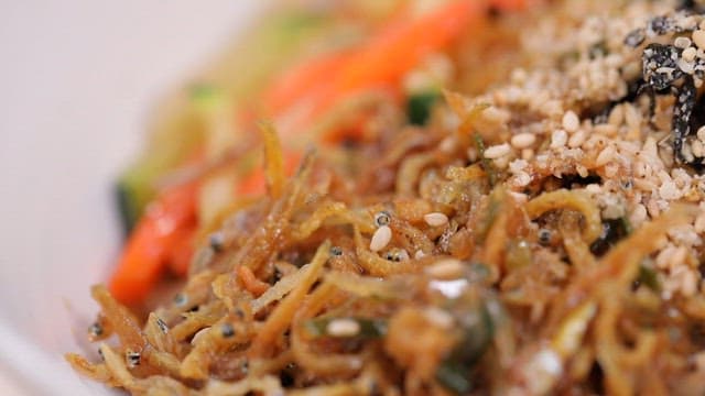 Anchovy bibim noodles topped with sesame seeds and seaweed powder