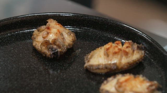 Grilled abalone on a black iron plate