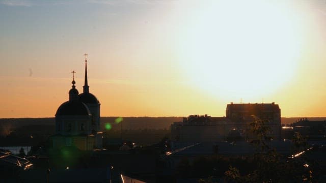 Sunset over a city with rooftops and church silhouettes
