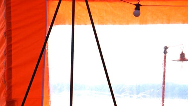 Hanging a camping lantern inside an orange tent