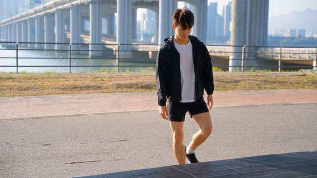 Man stretching by the riverside under a bridge