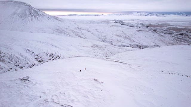 Snow-covered mountains with two hikers