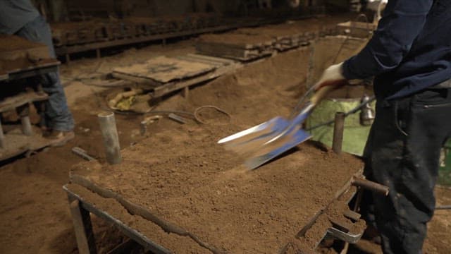 Worker shoveling sand in a factory