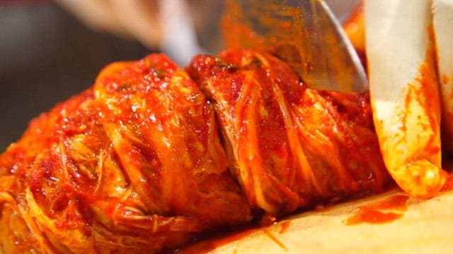 Kimchi being sliced on a cutting board