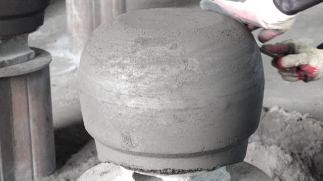 Wearing gloves and polishing the surface of an iron cauldron