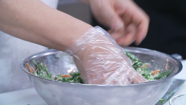 Making chive pancake batter in a stainless steel bowl with gloved hand