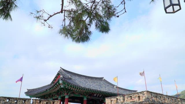 Entrance to an ancient Korean walled town with flags under a blue sky
