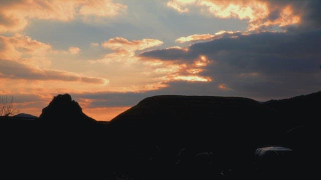 Sunset over silhouettes of hills and clouds