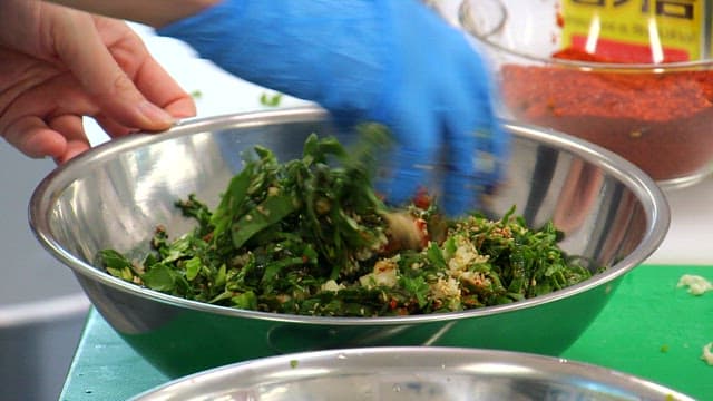 Mixing seasoned spinach in a bowl