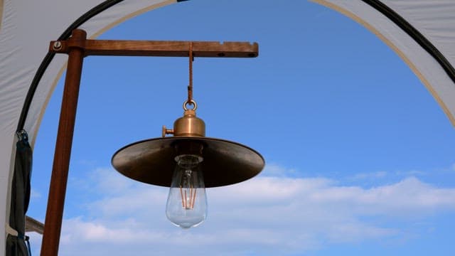 Vintage brass light bulb against a bright blue sky