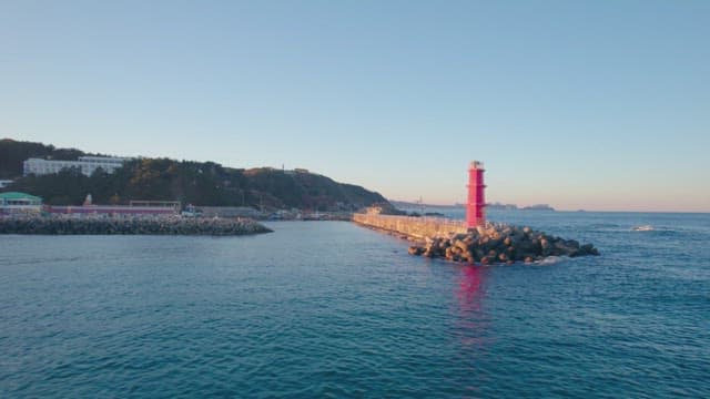 Red lighthouse by the blue sea at sunset