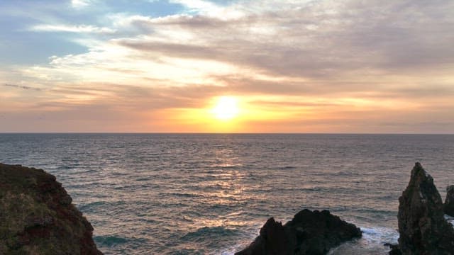 Sunset over the ocean with rocky cliffs