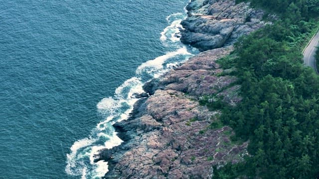 Waves Crashing on Rocky Coastline with Winding Roads
