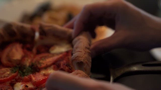 Person picking up a slice of pizza at a restaurant