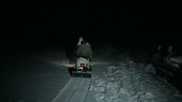 Snowmobile Crossing a Snow-Filled Night Landscape